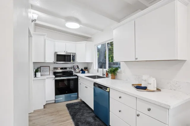 a kitchen with cabinets stainless steel appliances a sink and a window