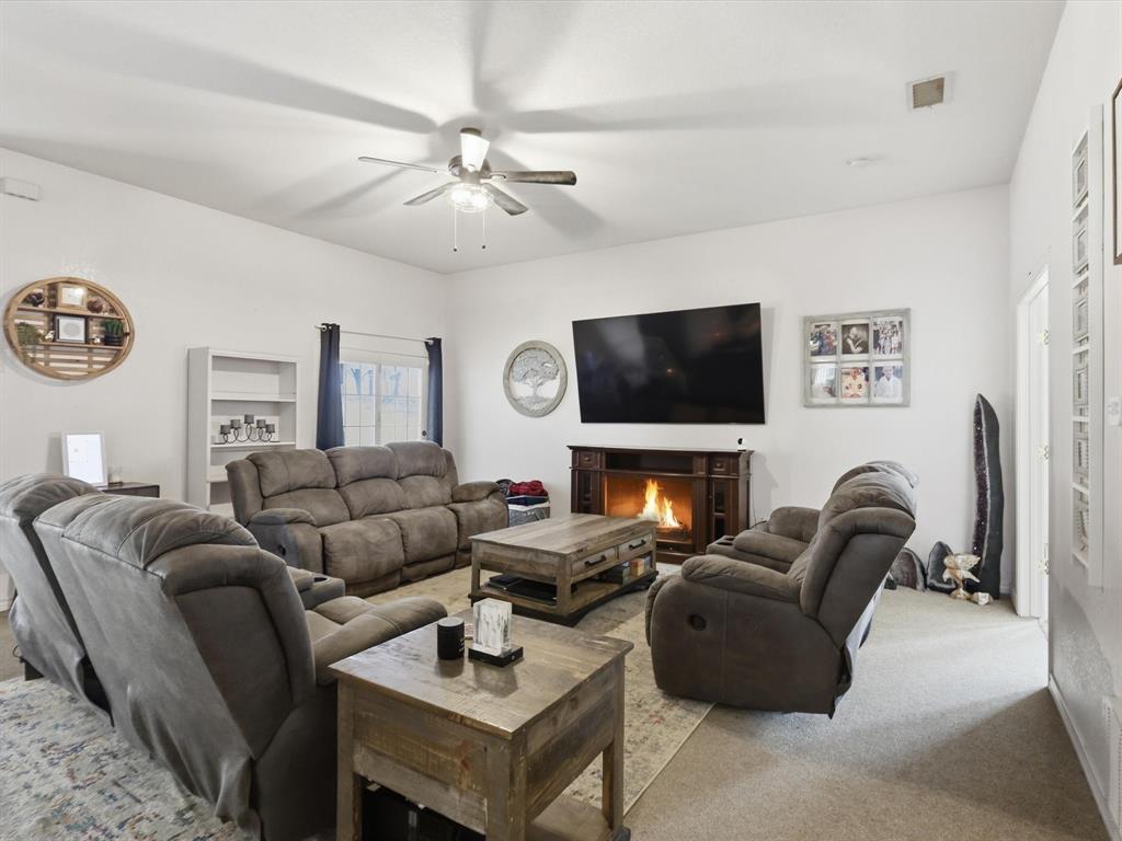 130 Parsonage Street Azle, TX 76020 - Photo 15 of 39 Living room with carpet, a lit fireplace, and a ceiling fan