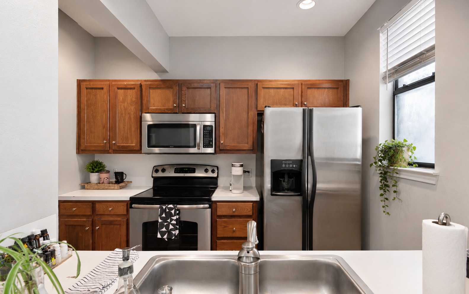 611 East 45th Street, Unit 25 Austin, TX 78751 - Photo 14 of 21 Stainless steel appliances, including a side-by-side refrigerator, microwave, and electric range, complement the warm wood cabinetry