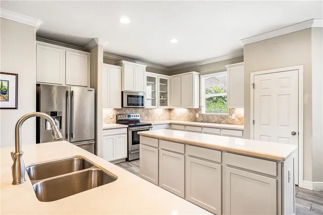 a kitchen with stainless steel appliances granite countertop a sink a stove a refrigerator with grey cabinets