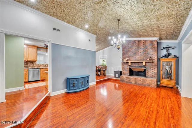 a view of a livingroom with a fireplace a chandelier and wooden floor