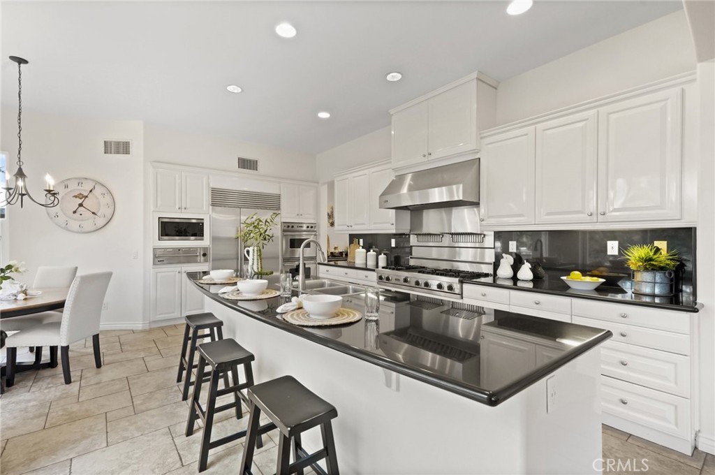 996 Blackbourne Point Oak Park, CA 91377 - Photo 19 of 75 a kitchen with stainless steel appliances granite countertop a sink a stove a kitchen island with chairs and white cabinets