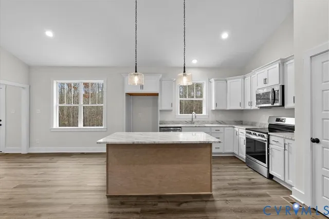 a kitchen with kitchen island granite countertop a stove a sink a center island and wooden floor