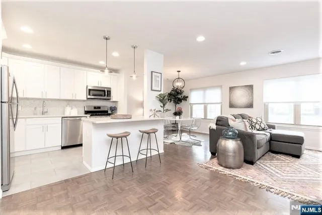 a large white kitchen with lots of counter space a sink appliances and cabinets