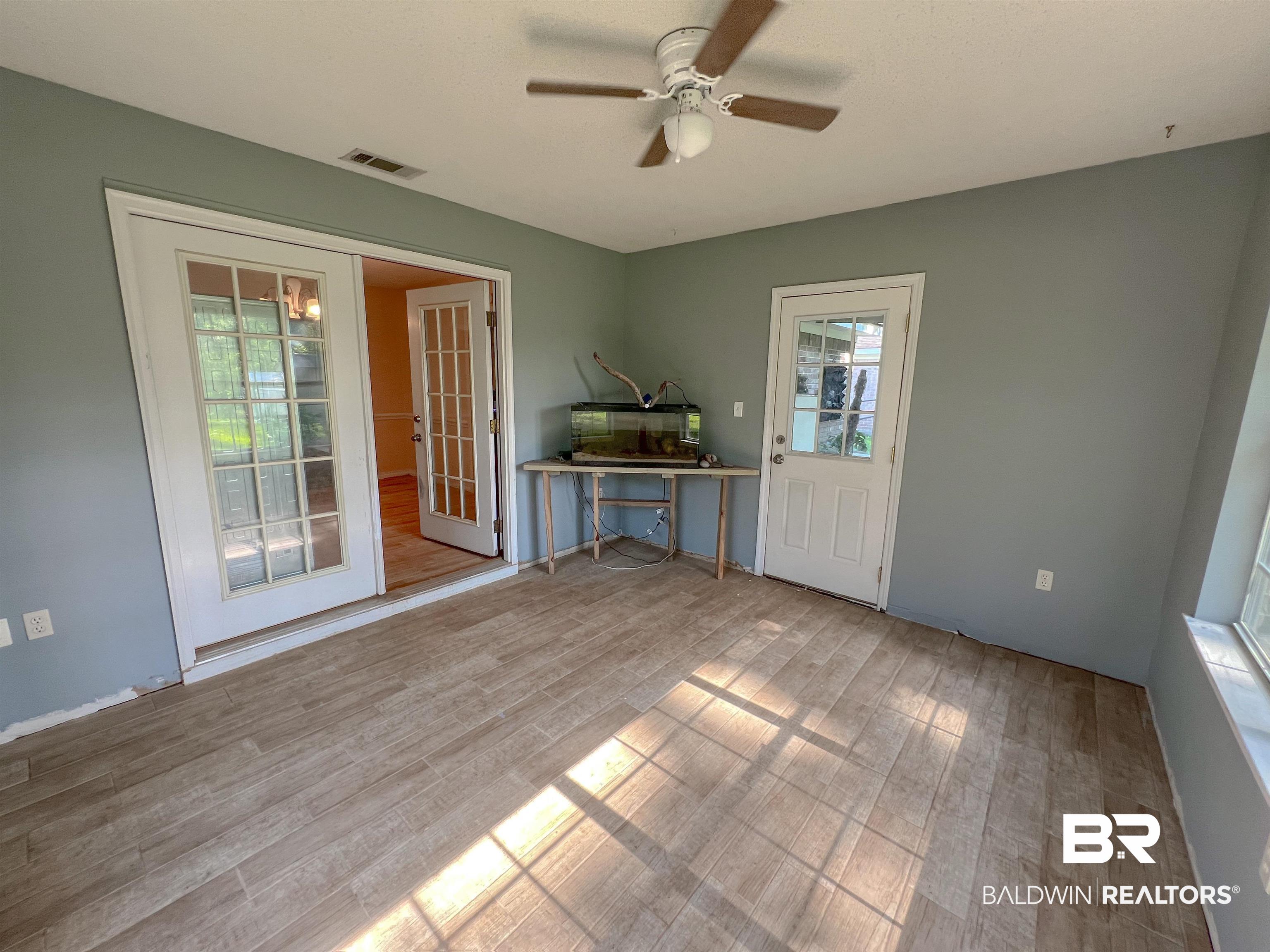 1200 South Juniper Street Foley, AL 36535 - Photo 6 of 23 Unfurnished room with ceiling fan, french doors, hardwood / wood-style flooring, and a healthy amount of sunlight