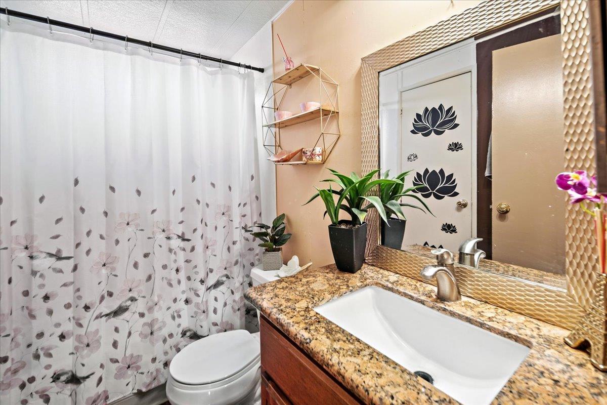 13607 Monte Del Sol, Unit 127 Castroville, CA 95012 - Photo 24 of 27 a bathroom with a sink a toilet and shower curtain