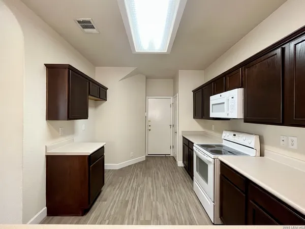 a kitchen with stainless steel appliances wooden cabinets and wooden floor
