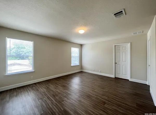 an empty room with wooden floor and windows