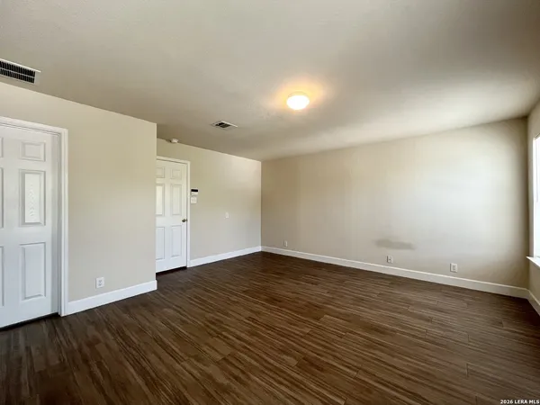 a view of an empty room with wooden floor and closet