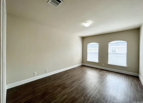 an empty room with wooden floor and windows