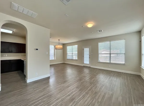 an empty room with wooden floor and windows