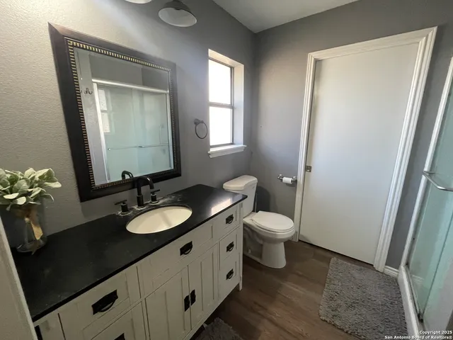 a bathroom with a granite countertop sink toilet and mirror