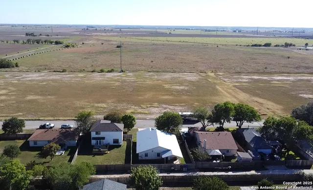 an aerial view of ocean and residential houses with outdoor space