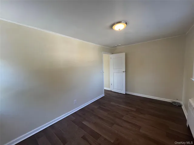 a view of an empty room with wooden floor and windows