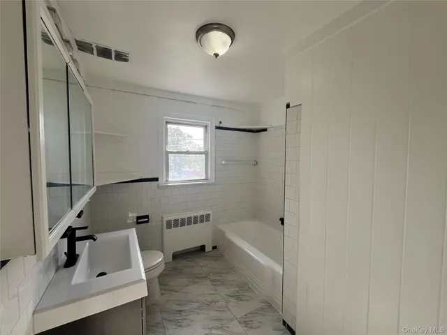 a bathroom with a tub sink vanity and a mirror
