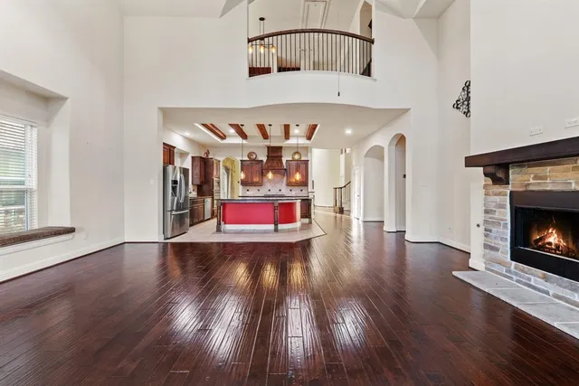 an empty room with wooden floor fire place and windows