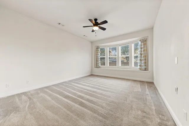 an empty room with wooden floor ceiling fan and windows