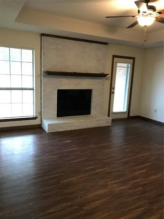 an empty room with wooden floor a fireplace windows and a fireplace