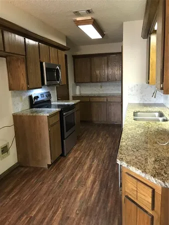 a kitchen with stainless steel appliances wooden cabinets a stove a sink and a microwave