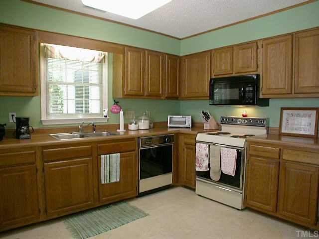 6902 Saxby Court Raleigh, NC 27613 - Photo 7 of 12 Great workspace. Electric Stove, Microwave, stainless steel sink, Dishwasher., faux stainless steel refrigerator, Oak Cabinets