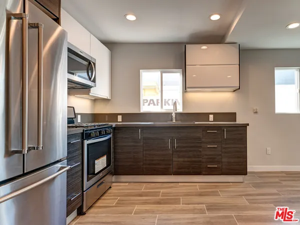 a kitchen with granite countertop a sink cabinets and stainless steel appliances