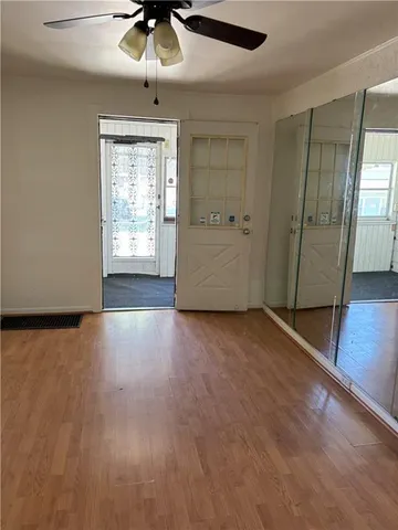 an empty room with wooden floor chandelier fan and windows