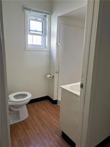 a bathroom with a toilet and a wooden floor