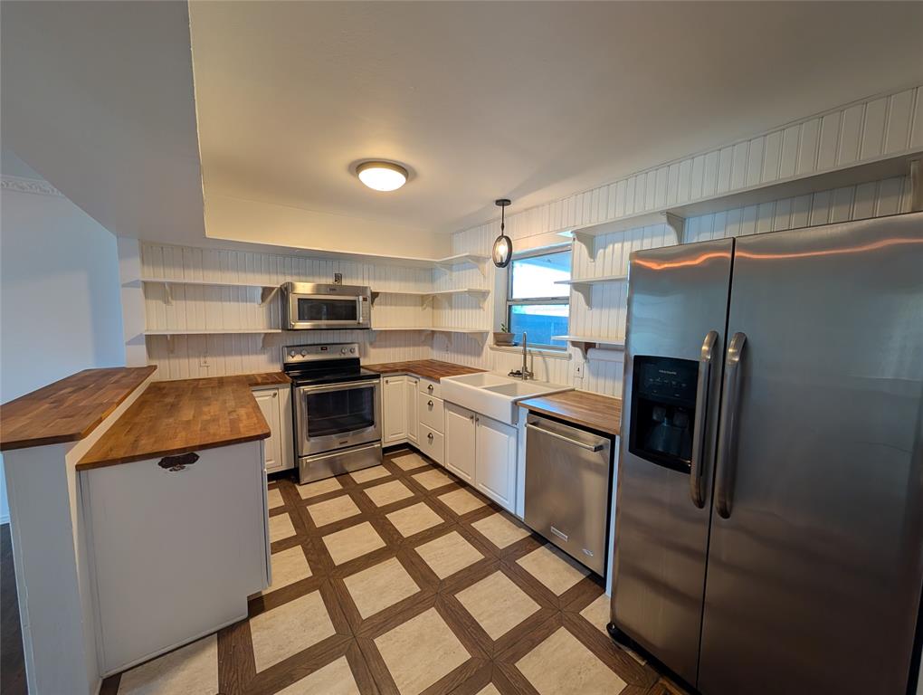 4715 Skillman Street, Unit A Dallas, TX 75206 - Photo 7 of 28 Kitchen featuring white cabinetry, wood-finish countertops, stainless steel appliances, and a farmhouse sink