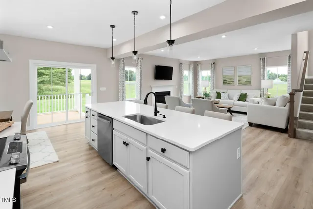 a large white kitchen with a large window a sink dishwasher a kitchen island with wooden floor and cabinets