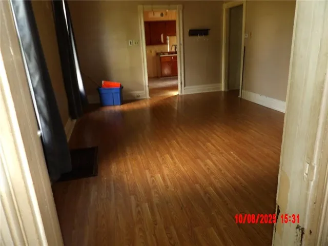 a view of an empty room with wooden floor and a window
