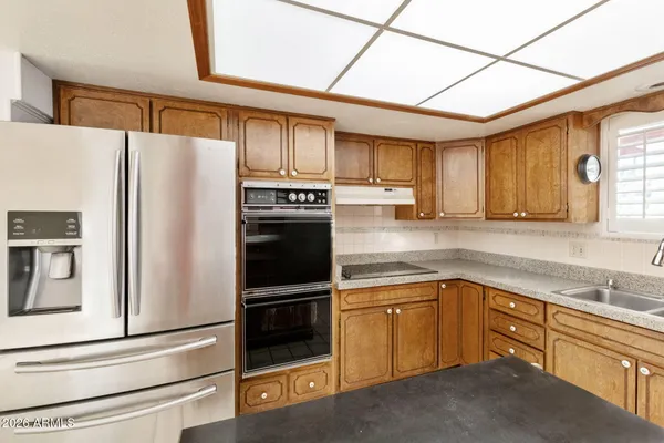 a kitchen with granite countertop a refrigerator and a stove top oven
