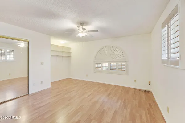 an empty room with wooden floor chandelier fan and windows