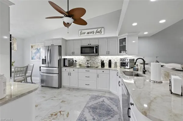 a dining room with stainless steel appliances kitchen island a table chairs and chandelier