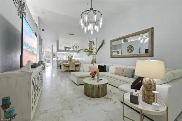 a living room with furniture a chandelier and a flat screen tv