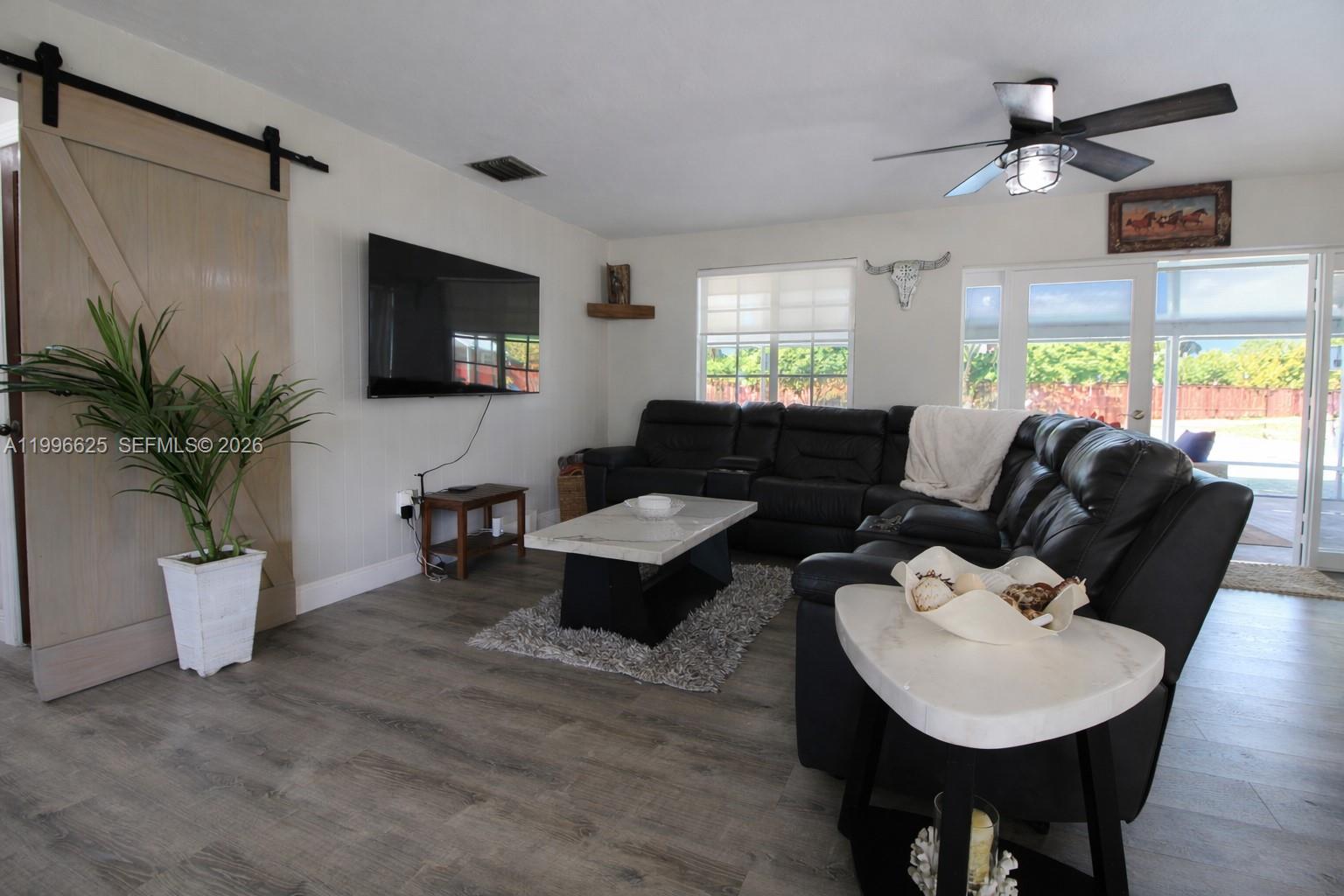 27420 Southwest 165th Avenue Homestead, FL 33031 - Photo 10 of 35 a living room with furniture a large window and a flat screen tv