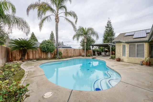 a swimming pool with outdoor seating and a garden