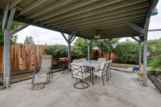 a view of patio with a table and chairs and couches with wooden fence and plants