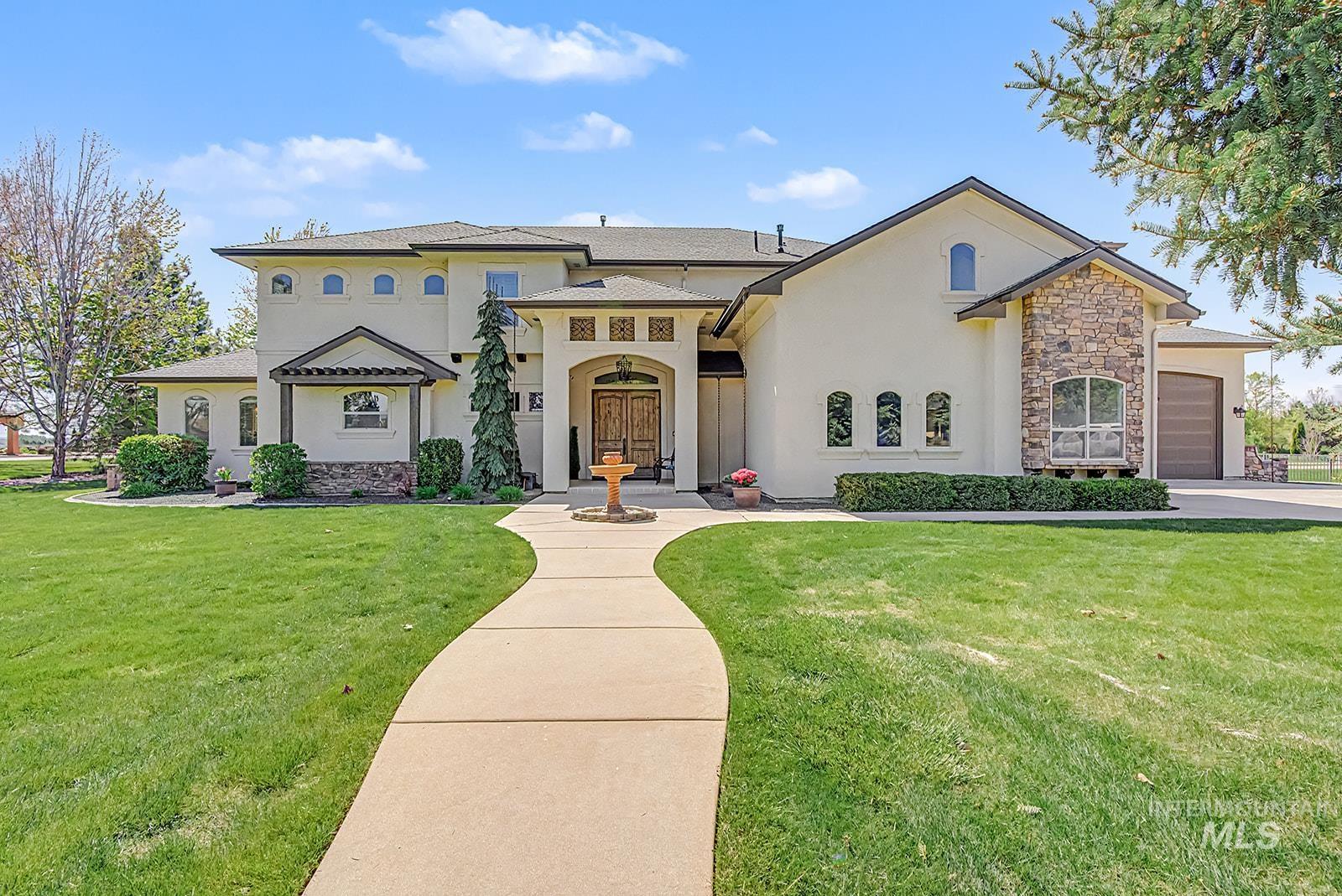 8751 West Rioja Street Star, ID 83669 - Photo 1 of 34 Stucco exterior with stone accents, featuring a prominent arched entry and double wooden doors