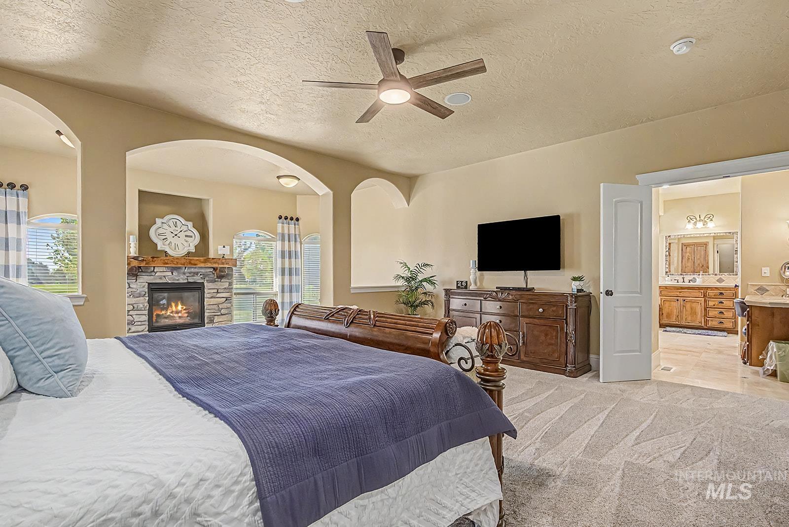 8751 West Rioja Street Star, ID 83669 - Photo 10 of 34 Spacious bedroom featuring vaulted ceilings, a stone-surround fireplace with a wood mantel, and plush carpet flooring