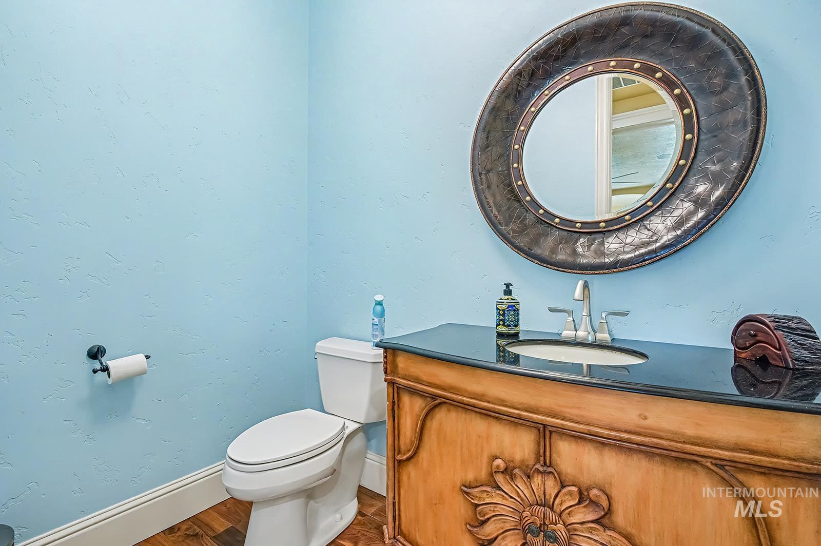 8751 West Rioja Street Star, ID 83669 - Photo 14 of 34 Powder room featuring a decorative wood-finish vanity with an integrated sink, dark countertop, and a large round mirror