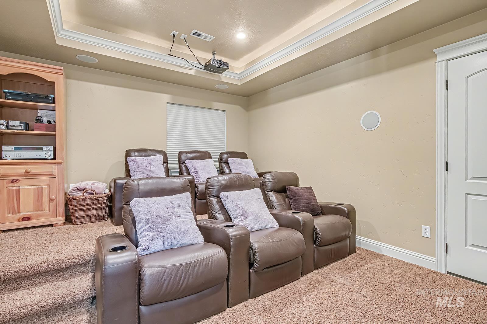 8751 West Rioja Street Star, ID 83669 - Photo 16 of 34 Dedicated entertainment room featuring tiered seating, built-in ceiling speakers, a projector, and tray ceiling with recessed lighting