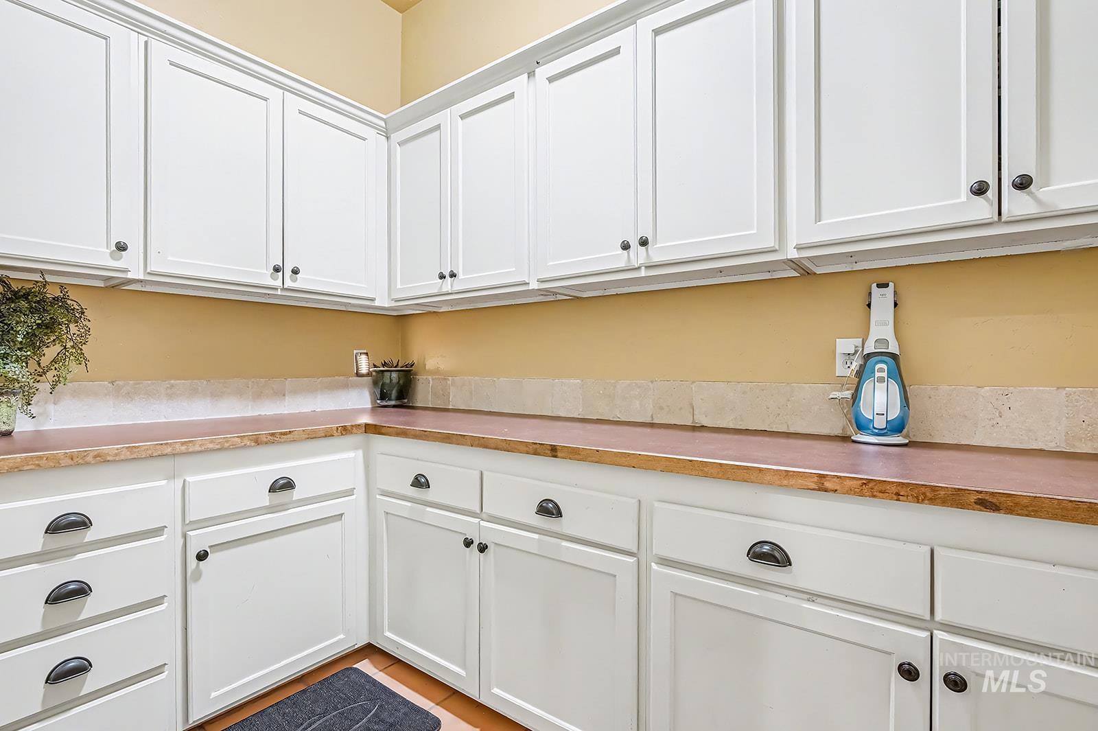 8751 West Rioja Street Star, ID 83669 - Photo 25 of 34 Extensive white cabinetry with varied hardware, complemented by a light-toned backsplash and wood-finish countertops