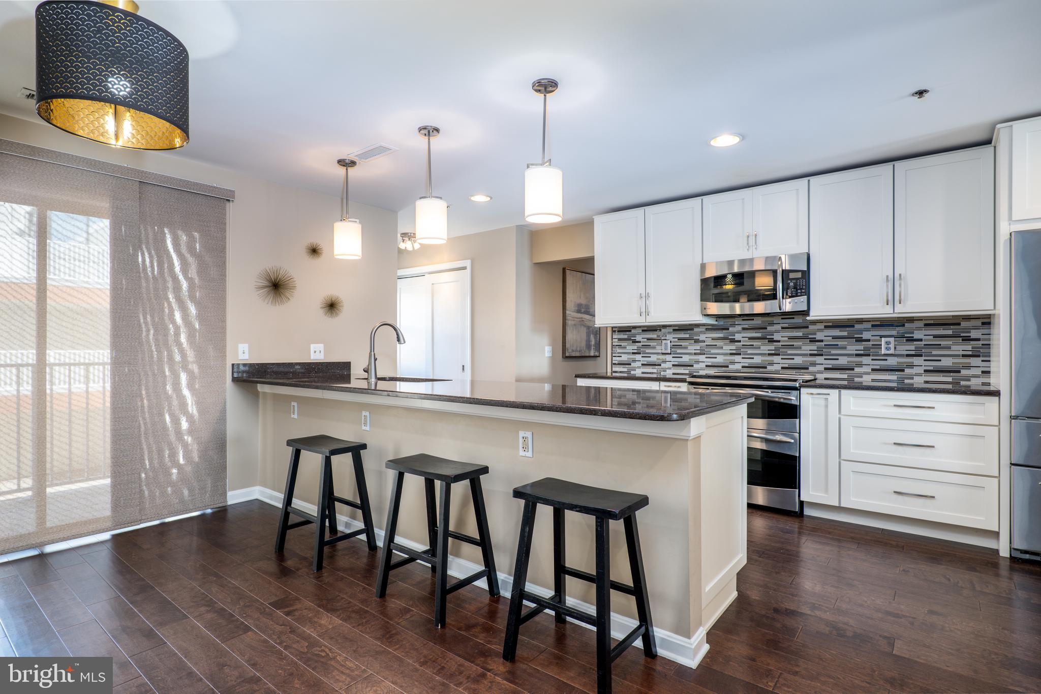 2702 Lighthouse Point East, Unit 637 Baltimore, MD 21224 - Photo 13 of 37 a kitchen with kitchen island granite countertop a stove a sink a center island and wooden floor