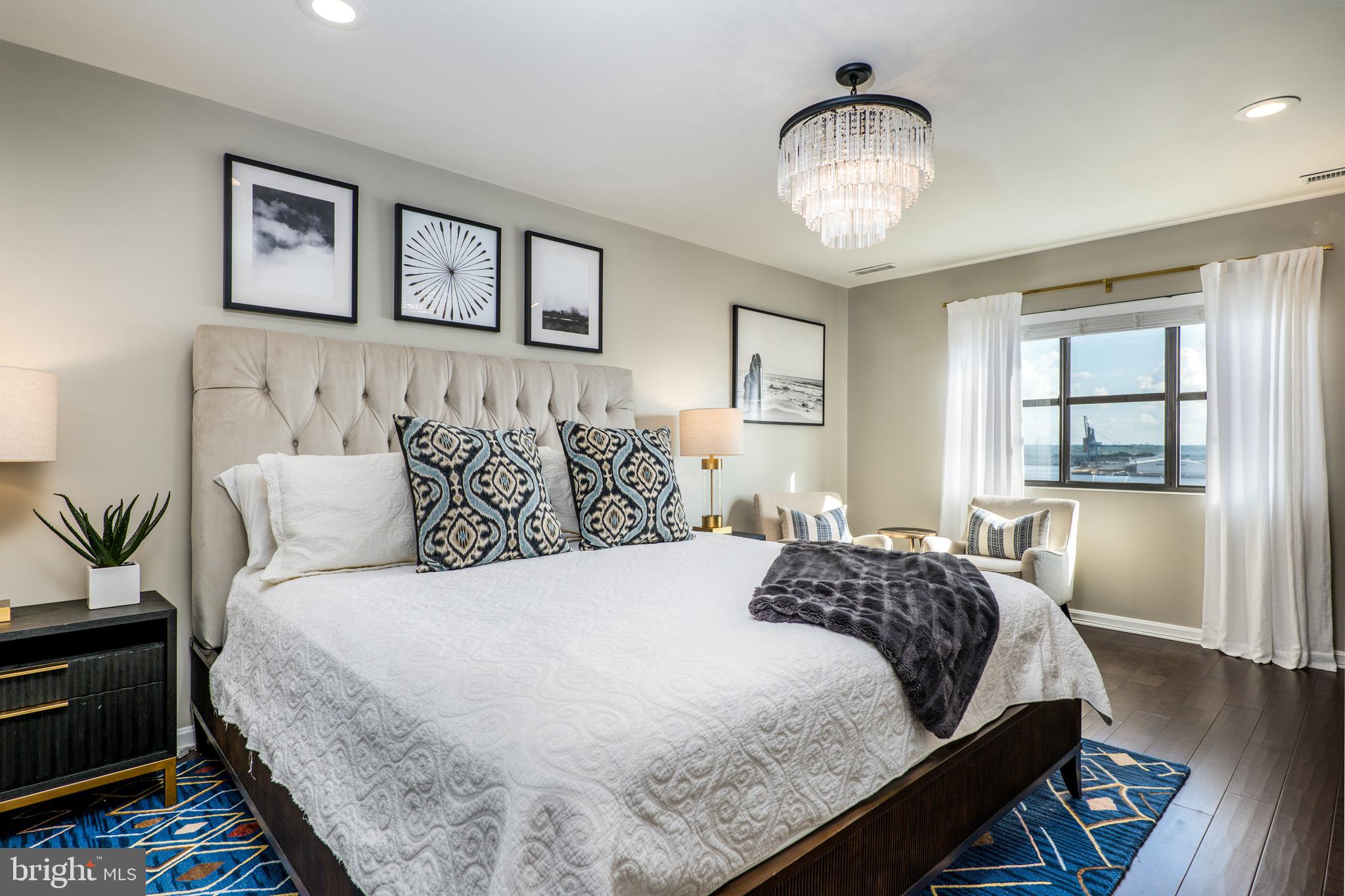 2702 Lighthouse Point East, Unit 637 Baltimore, MD 21224 - Photo 19 of 37 a bedroom with a bed and a chandelier