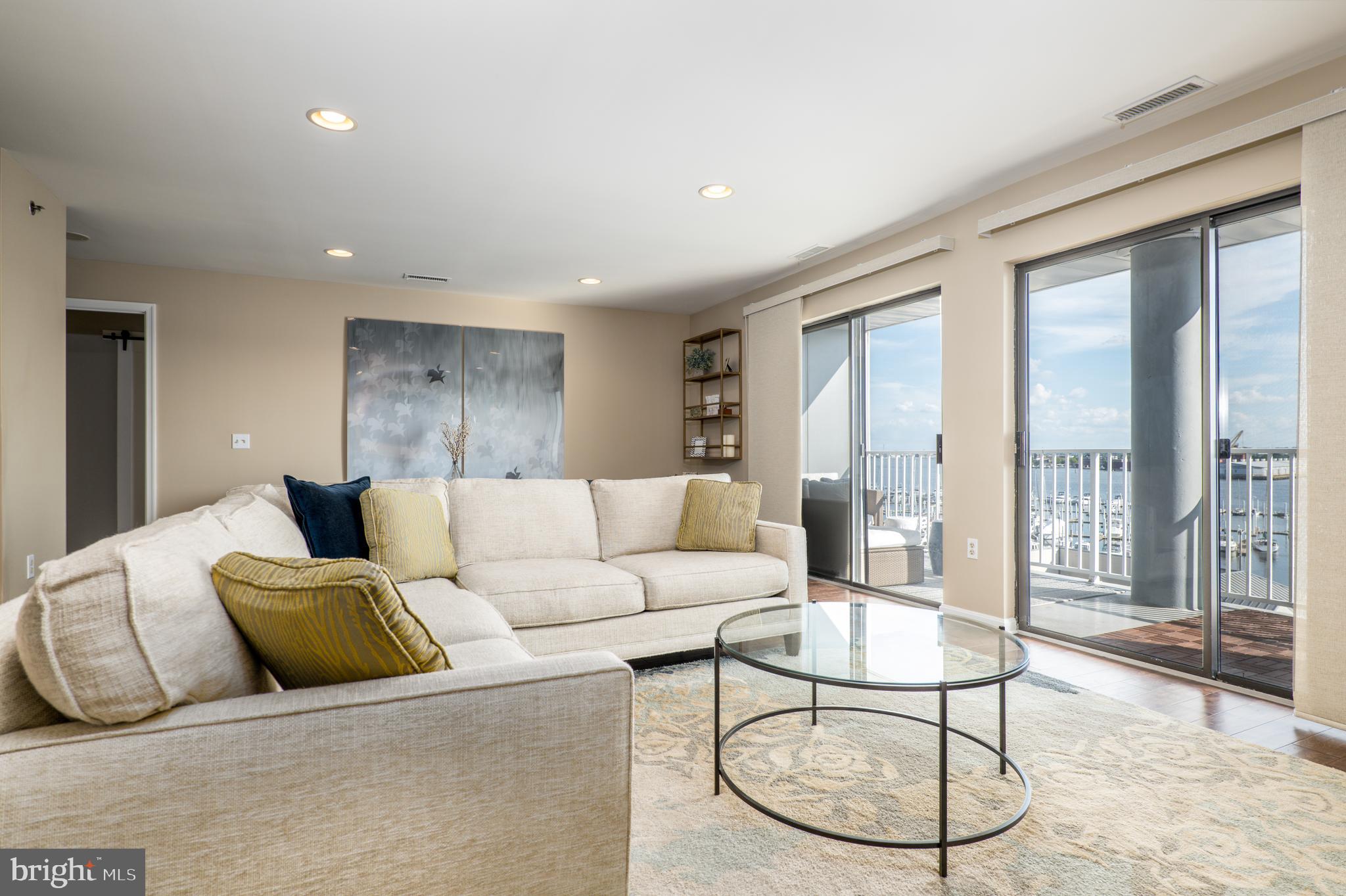 2702 Lighthouse Point East, Unit 637 Baltimore, MD 21224 - Photo 8 of 37 a living room with furniture a large window and wooden floor