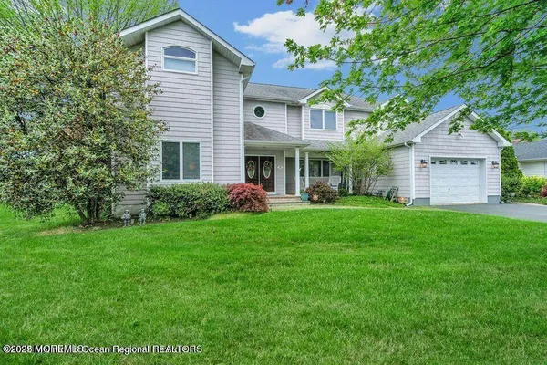 a front view of a house with a garden and trees