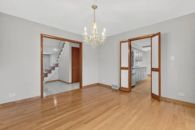 a view of a room with wooden floor chandelier and windows