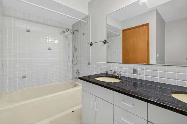 a bathroom with a granite countertop tub sink and mirror