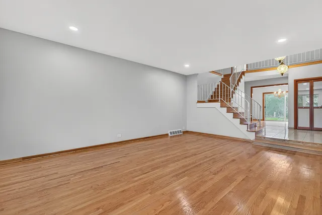 a view of an empty room with wooden floor and stairs
