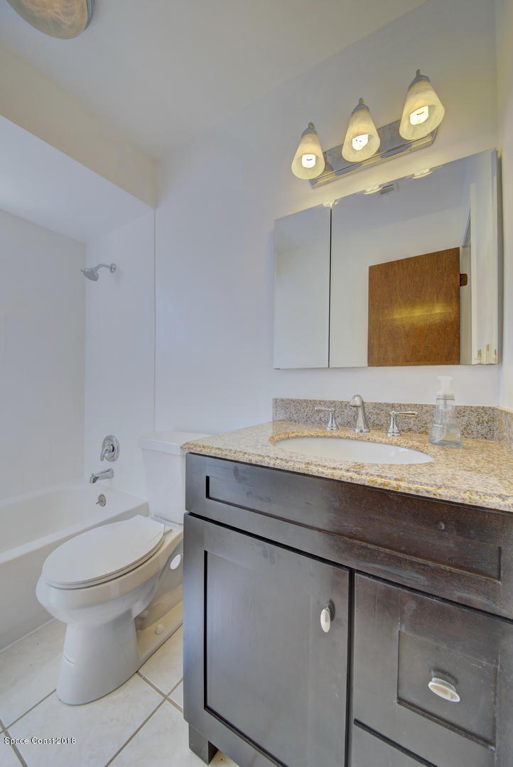1005 Audubon Road Merritt Island, FL 32953 - Photo 24 of 39 a bathroom with a granite countertop toilet sink mirror and vanity